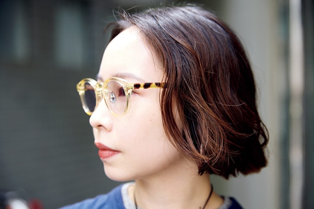 アヤメのクリアフレームのメガネは、サイドのべっ甲と、着こなしに抜け感を出してくれるところが◎。