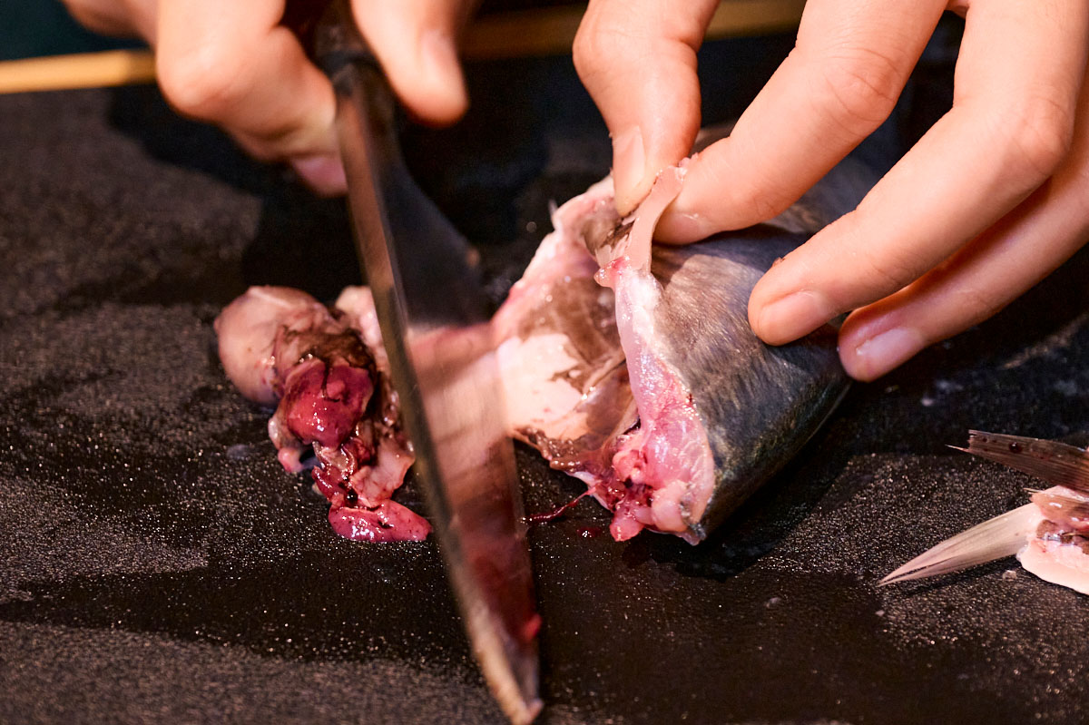 肛門から腹に向かって包丁を入れたら、刃先で内臓をかき出します。内臓を傷つけないよう、ていねいに行って。