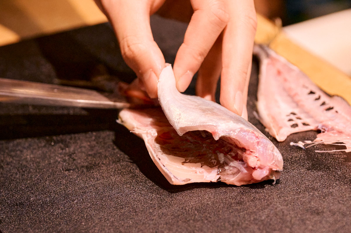 まずは片面からおろします。腹側に包丁を入れ、中骨に沿って滑らせながら、真ん中にある太い骨まで引いていきます。