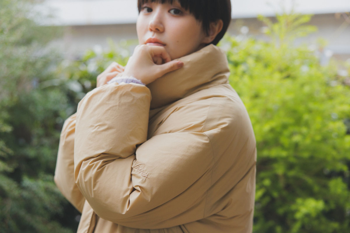 NANGA（ナンガ）のスタンドカラーダウンジャケットを着た奈緒さん。ゆったりしたシルエットと高めの襟が冬の寒さを包み込み、女性らしい軽やかさを演出。