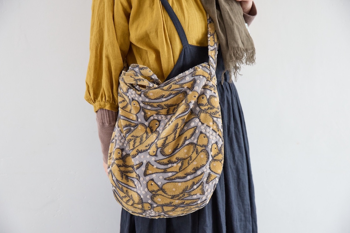 冬のナチュラルレイヤードスタイルに合わせたミナ ペルホネンの柄バッグ