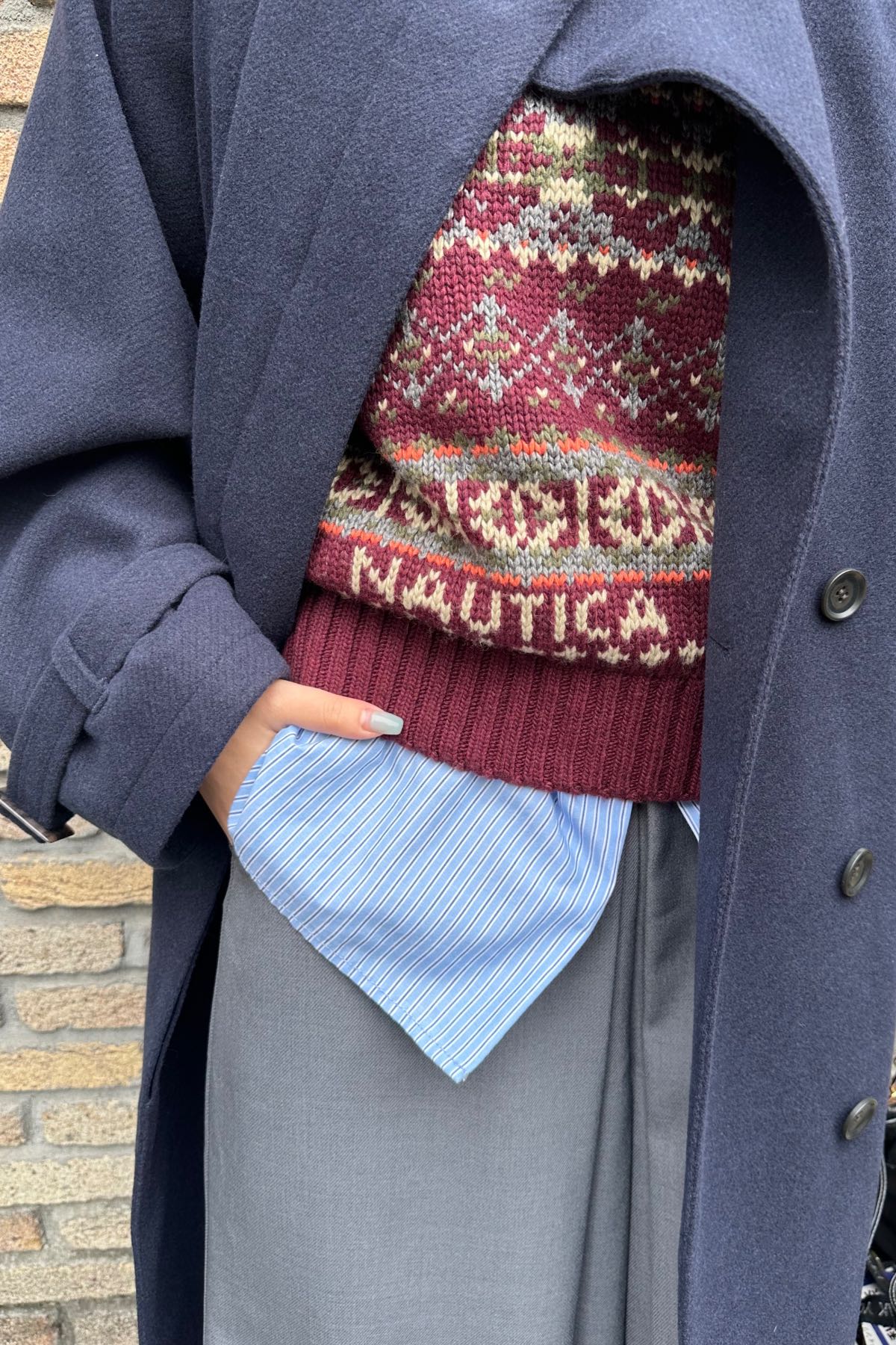 フェアアイル柄ベストにブルーのストライプシャツを重ねたレイヤード