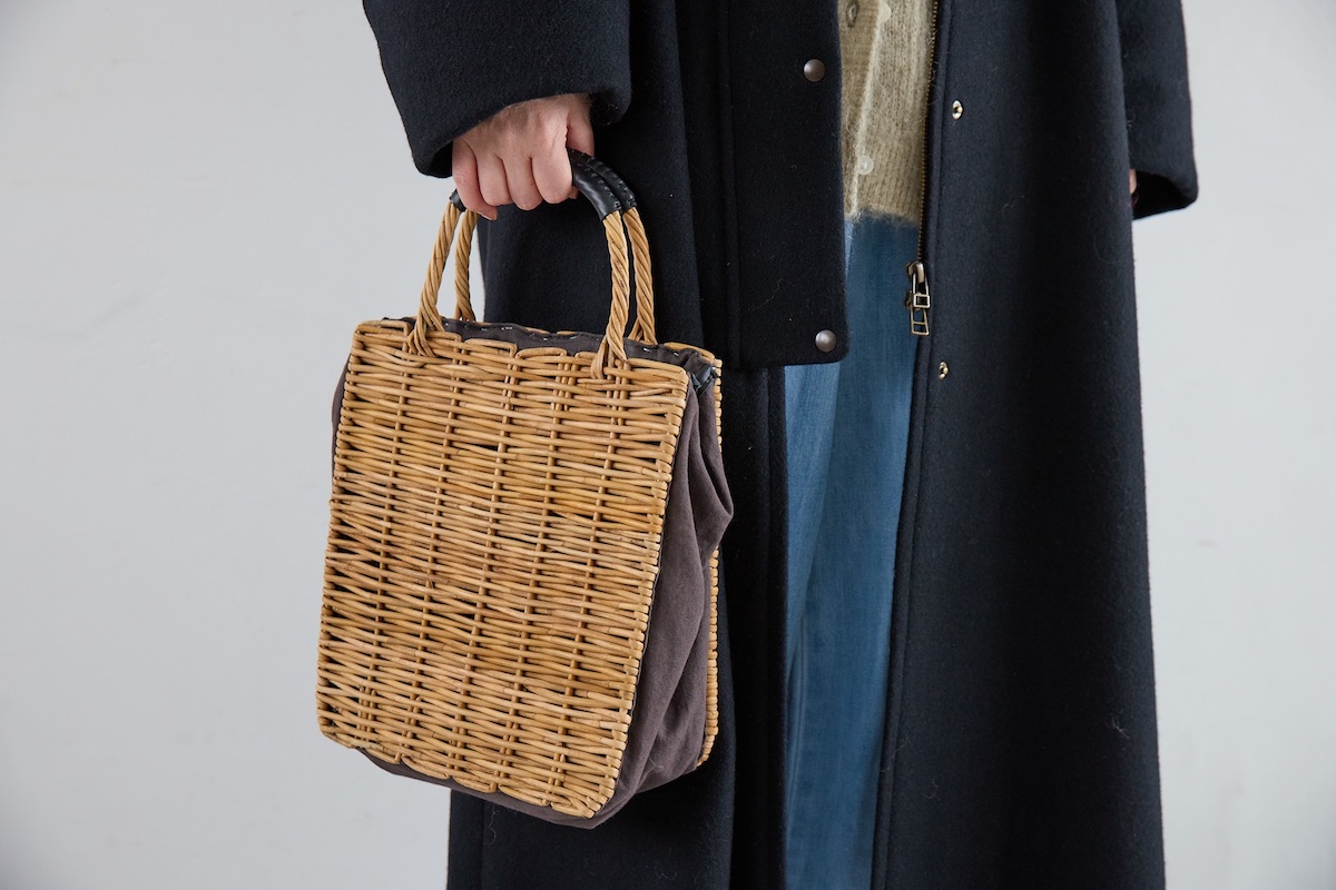 黒のロングコート×デニムパンツに合わせたロワズィールの籐素材のバッグ