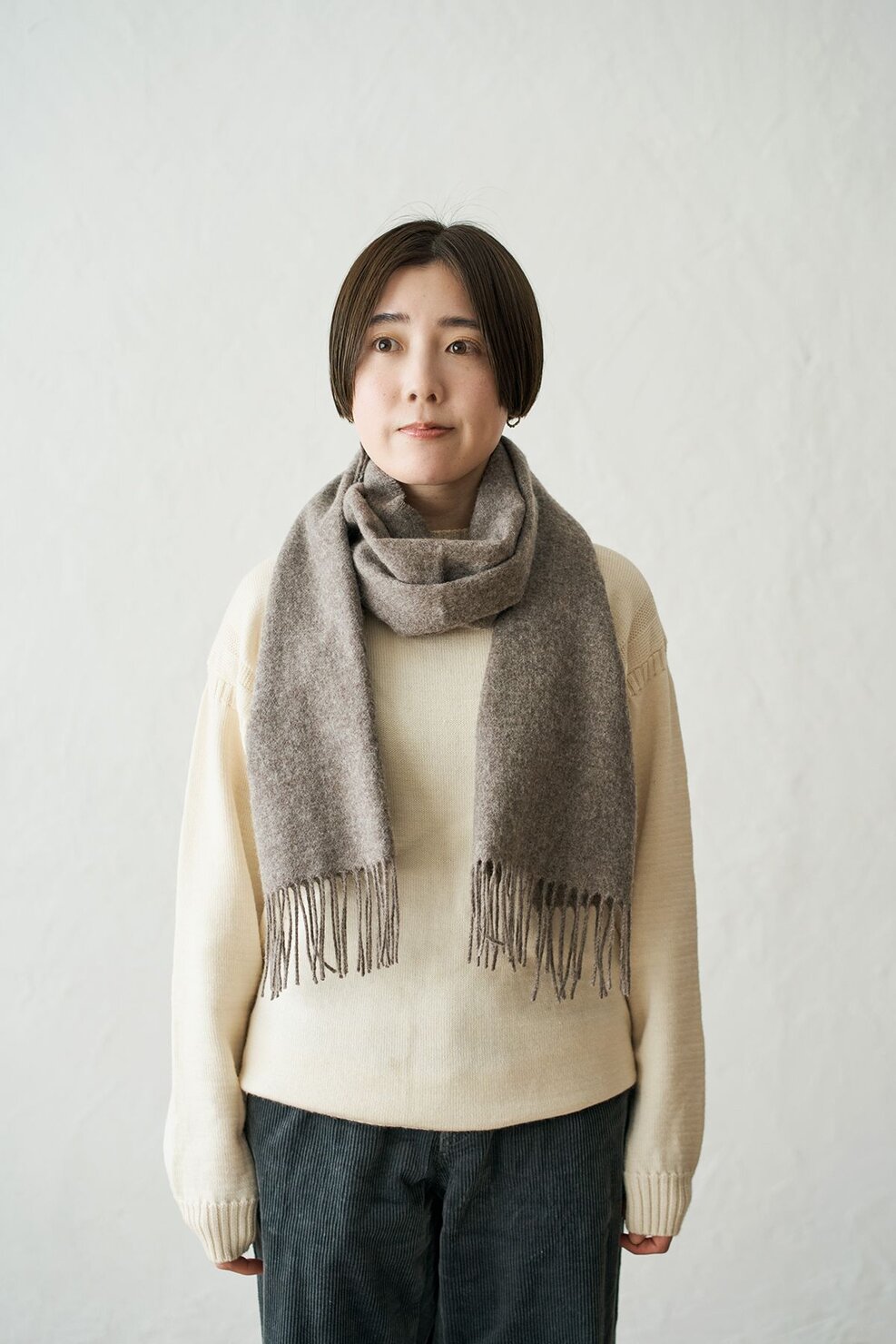 マフラーを首の前からかけて後ろでクロスし、両端を前に垂らす