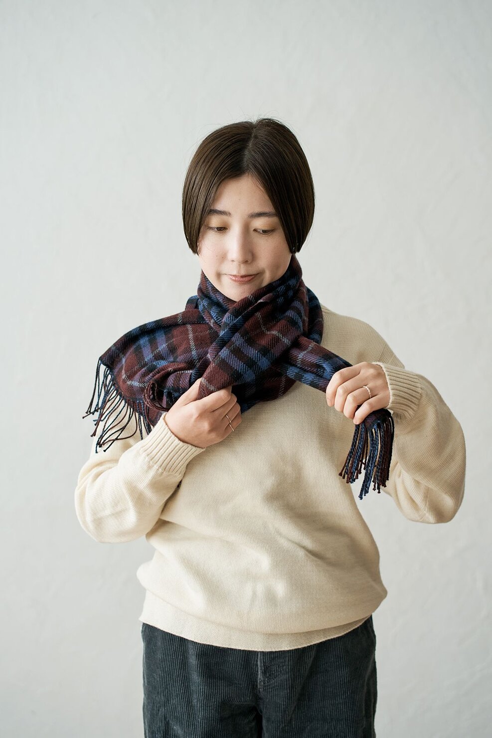 手前から巻いたマフラーを、押さえている方の手に持ち替えて輪っかに通す