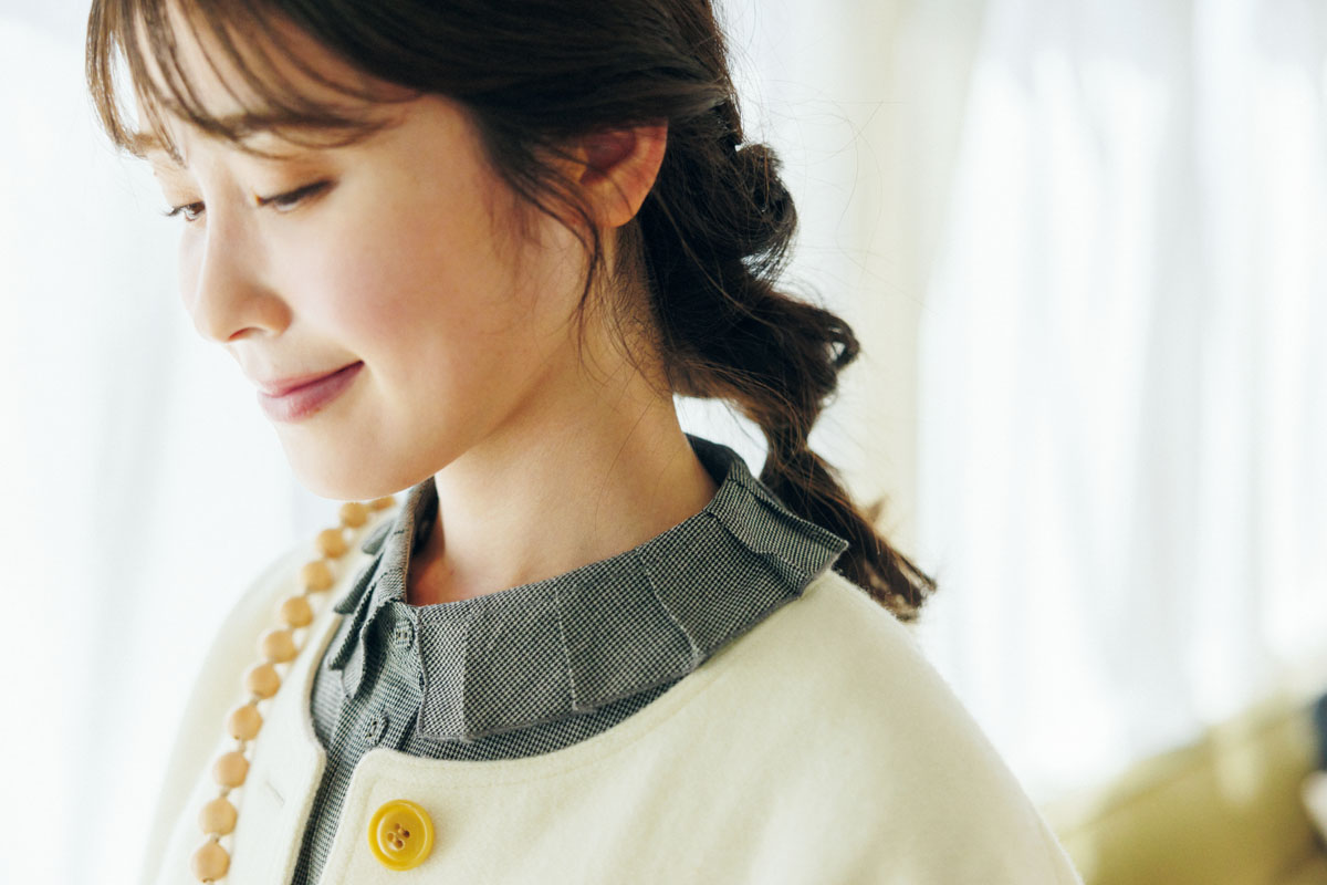 ノーカラーのコートからブラウスの襟をのぞかせて、さりげないアクセントに