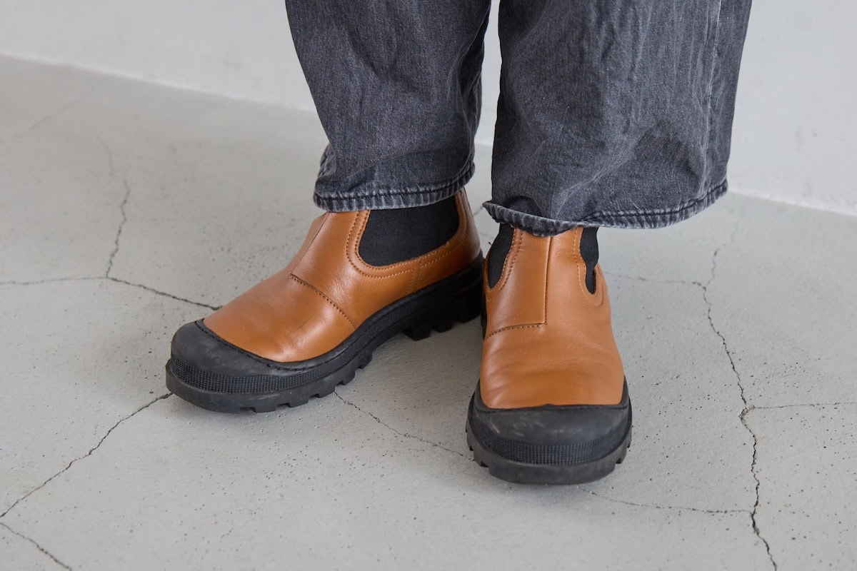 デニムパンツに合わせた、オレンジブラウンの色味が映えるロエベのレザーブーツの足もと