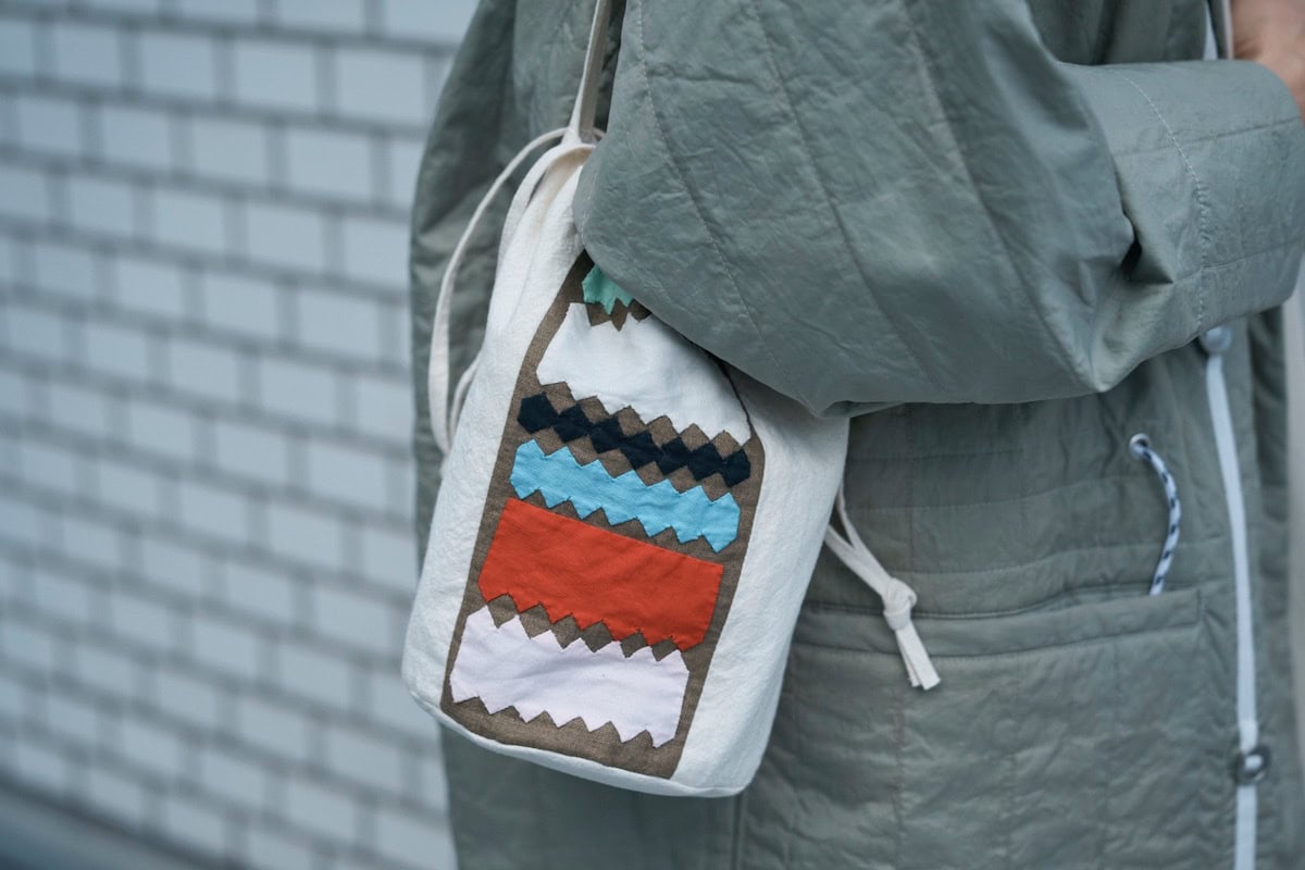 赤をポイントで効かせた、パッチワークデザインの小ぶりな巾着型バッグ