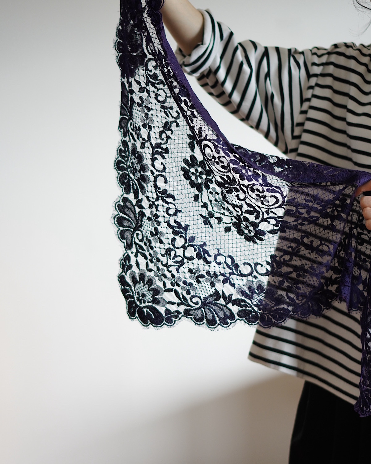 ネイビーレーススカーフを広げて見せている
