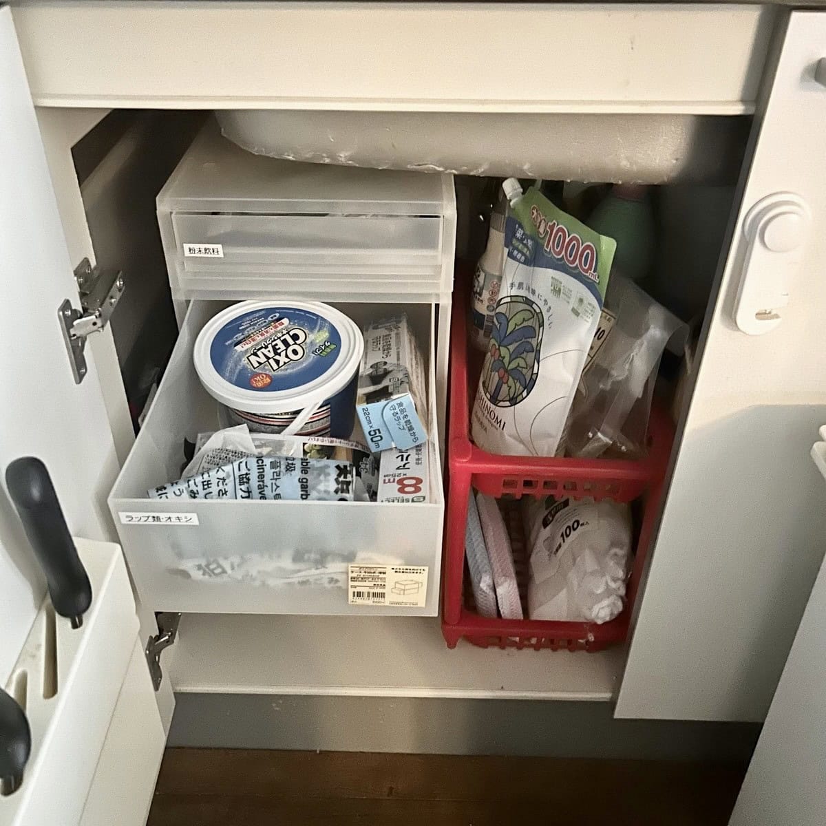 既存の扉付き収納の中にラップやごみ袋、洗剤などを隠した様子。