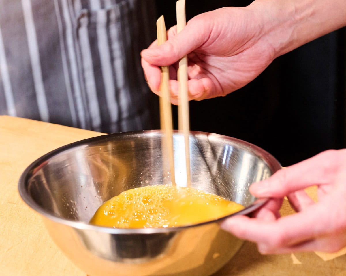 ボウルの卵を混ぜる手もと