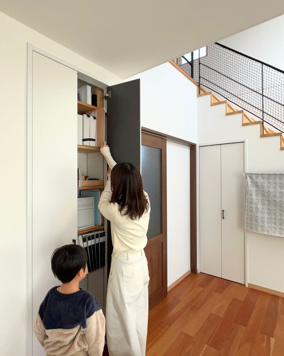 リビング収納から子どもの作品集を取り出す様子