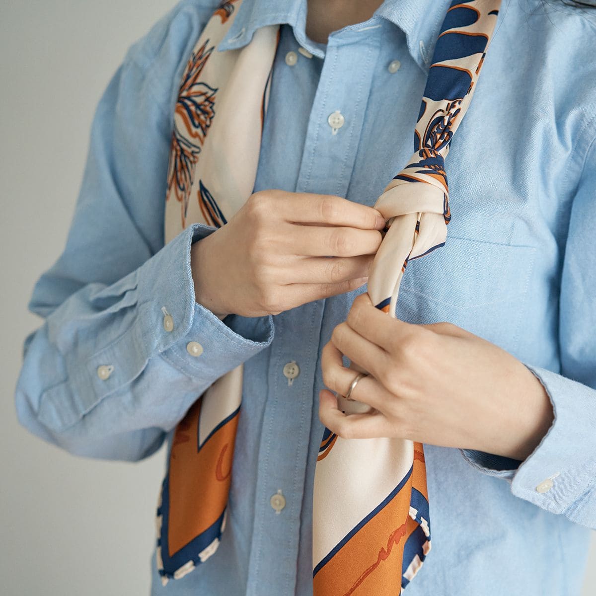 首に掛けて長めに伸ばしたスカーフに、結び目をつくる