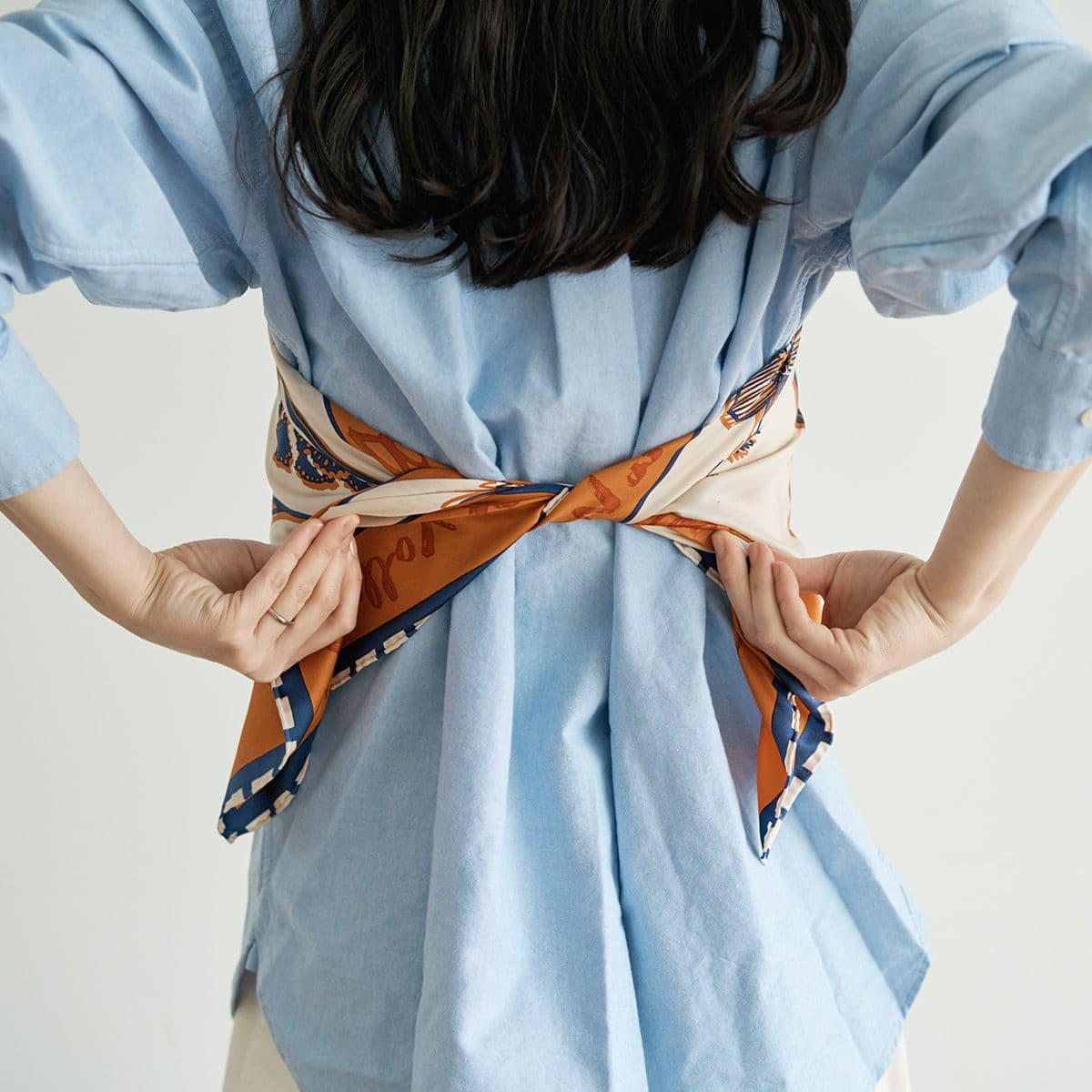 胸に当てたスカーフを、後ろで一度結びます