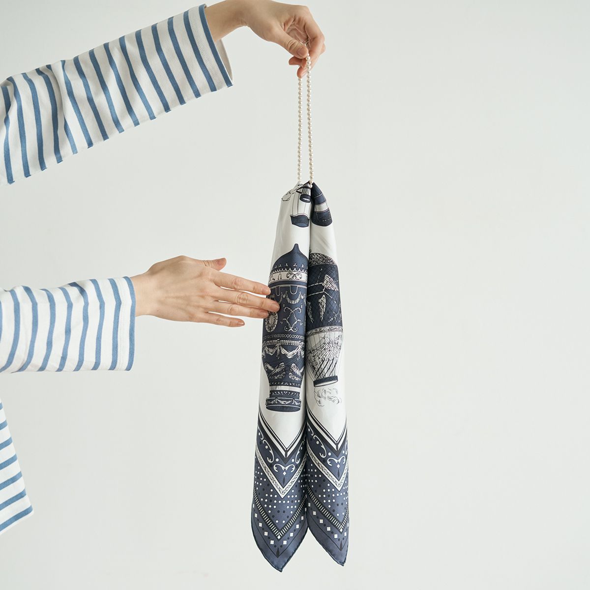 ネックレスの金具部分を覆うように、スカーフを片側へ寄せる