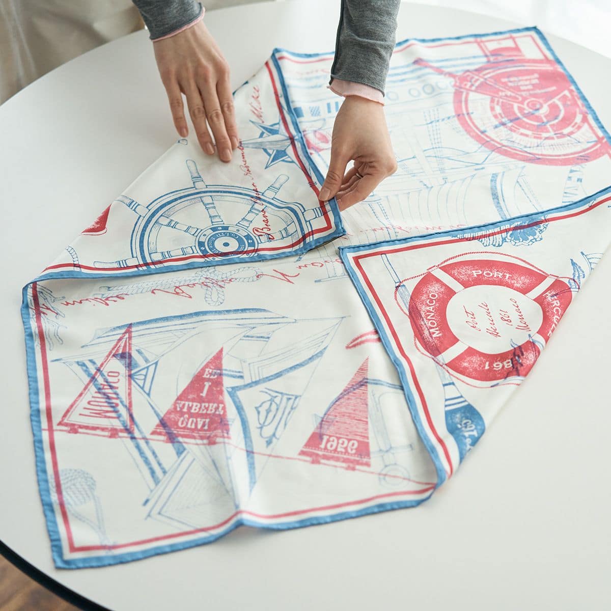 スカーフを裏返して広げ、対角の端を中心に向かって折ります