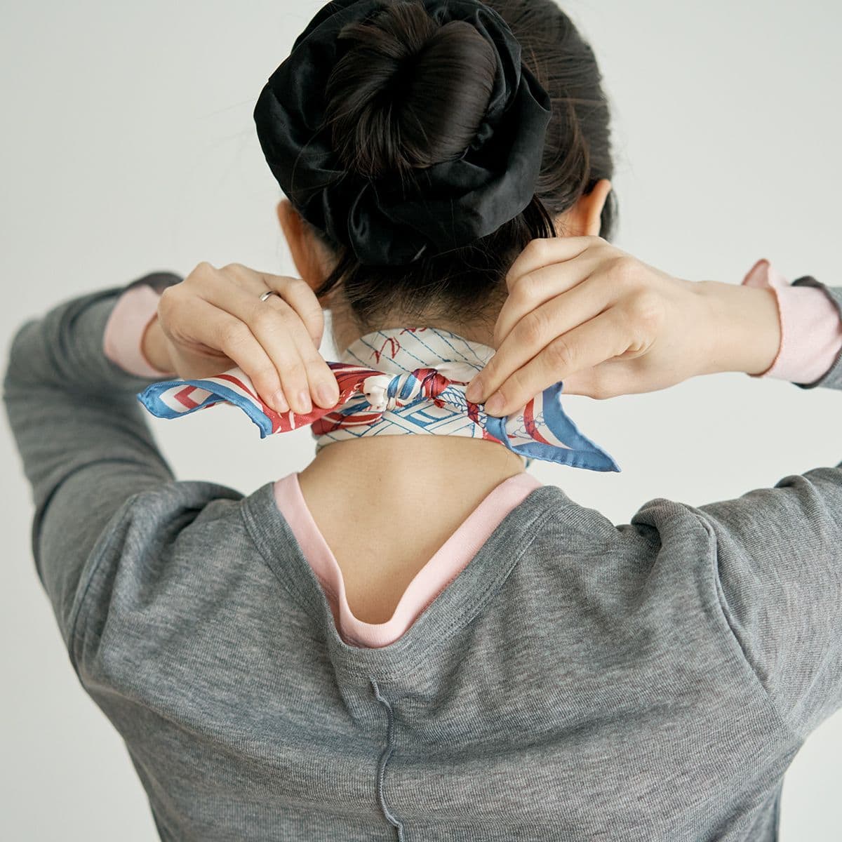 首の前でクロスしたスカーフの両端を、背中側にまわして結ぶ