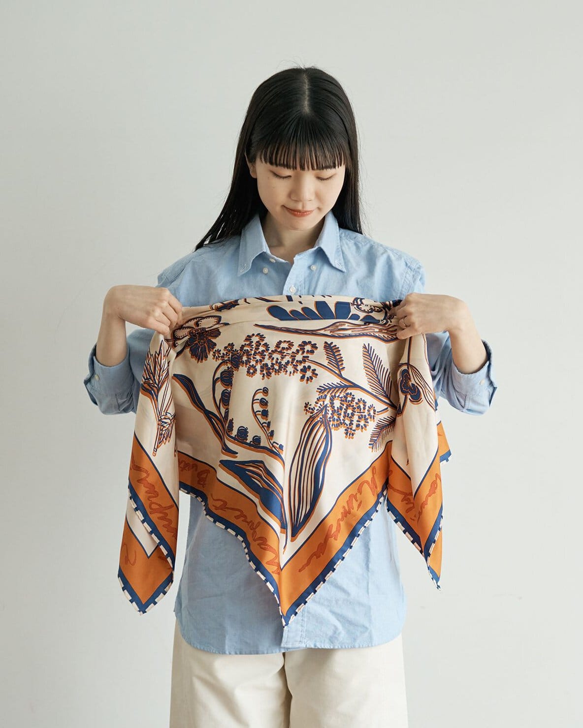 三角形に折ったスカーフの上部が、胸の上のラインにくるように当てる