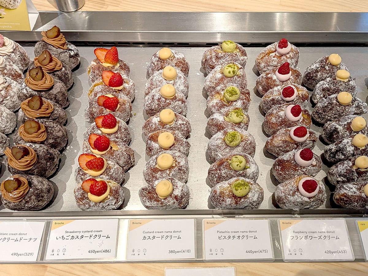 I'm donut ? 自由が丘店の陳列されたクリーム入りドーナツなど、たくさんのドーナツ。