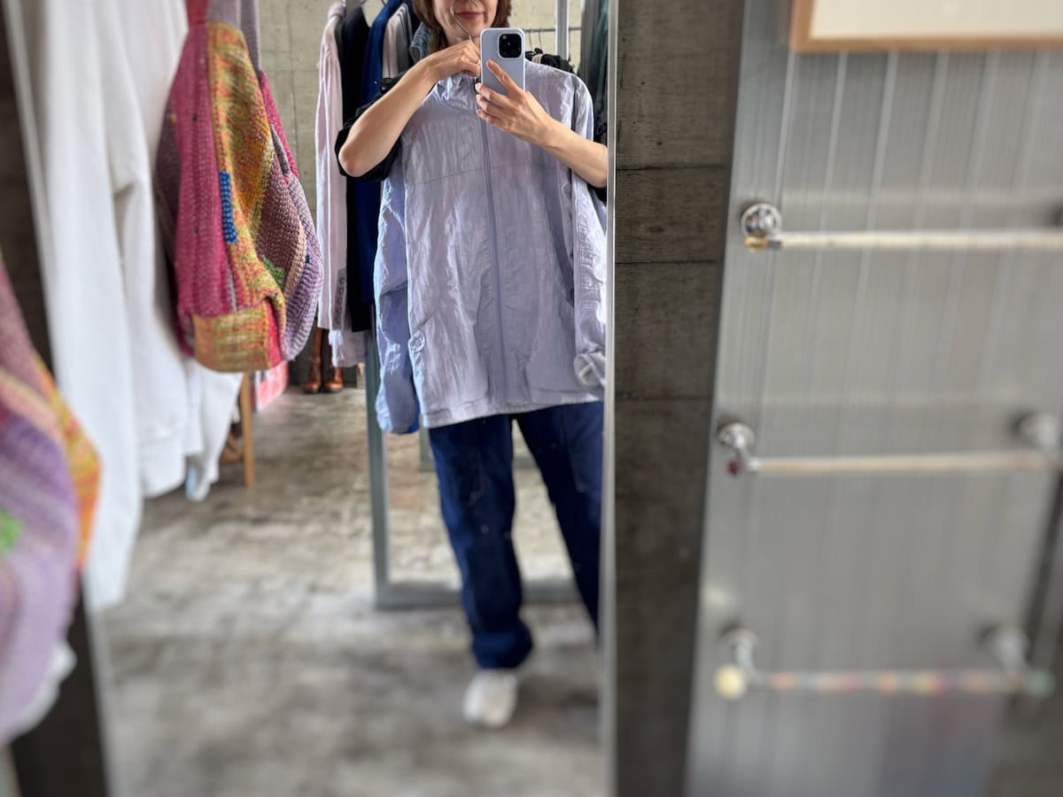 多摩市落合商店街の古着店SAJIでラベンダー色のアウターを鏡で合わせている様子