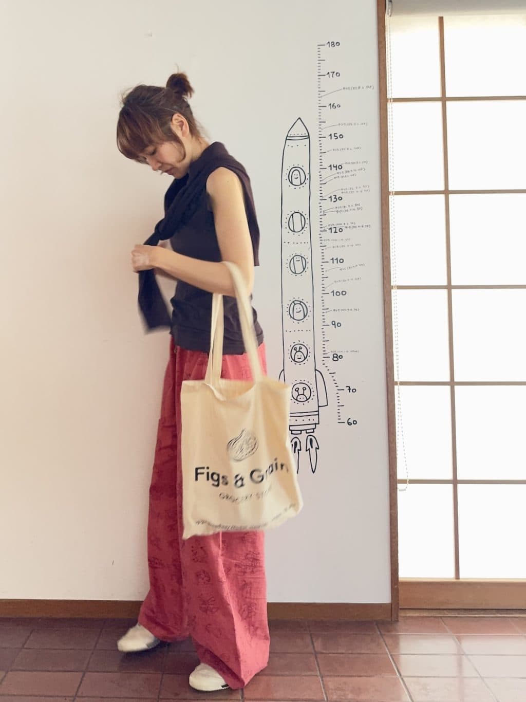 ピンクの柄パンツにブラウンのトップスを合わせたコーデ。白小物が抜け感。