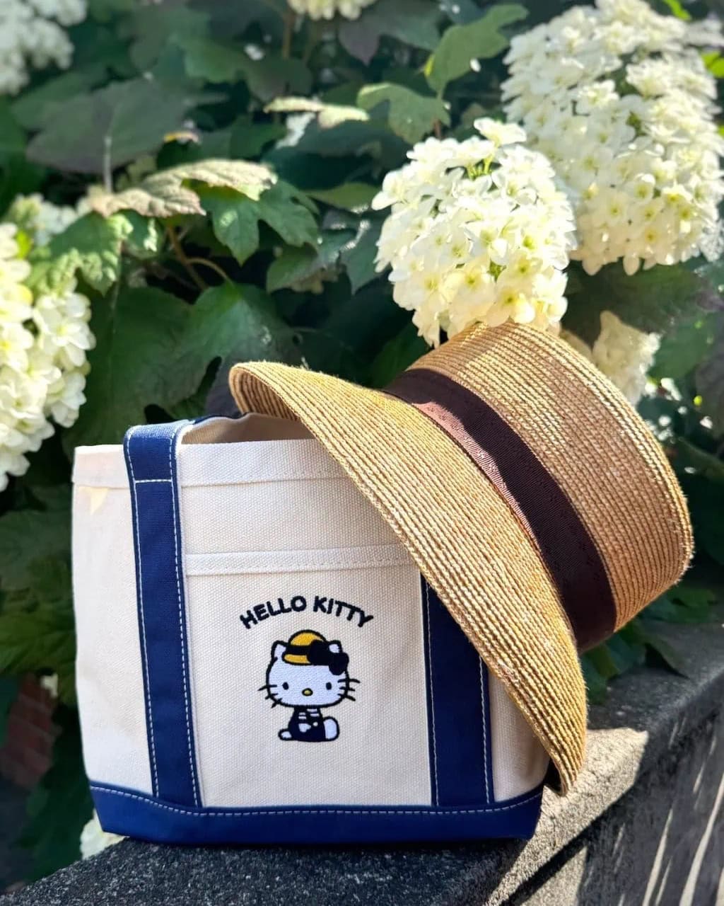 リンネル8月号付録のハローキティランチトートバッグに麦わら帽子を合わせて、紫陽花を背景に撮影