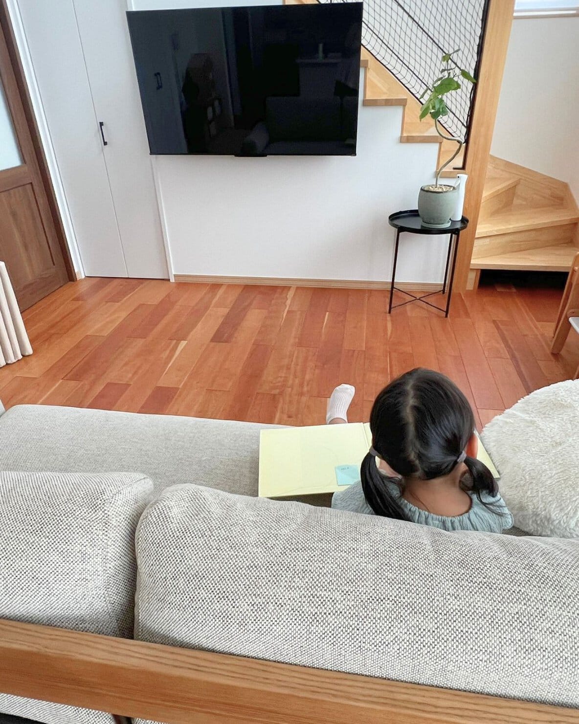 北欧モダンなソファーでくつろぎながら読書をする女の子