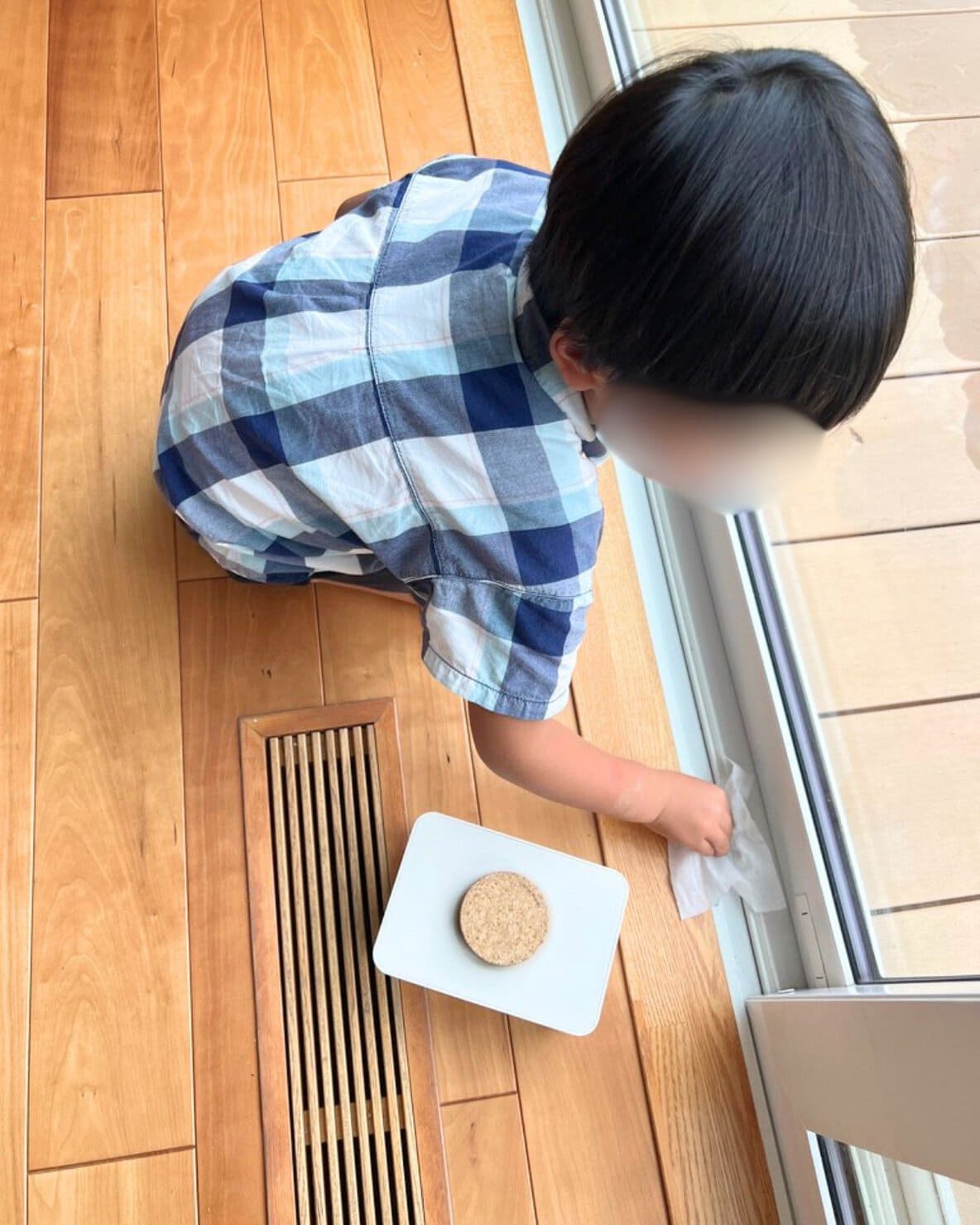 お気に入りのウェットティッシュケースとウェットティッシュで窓枠を掃除する男の子