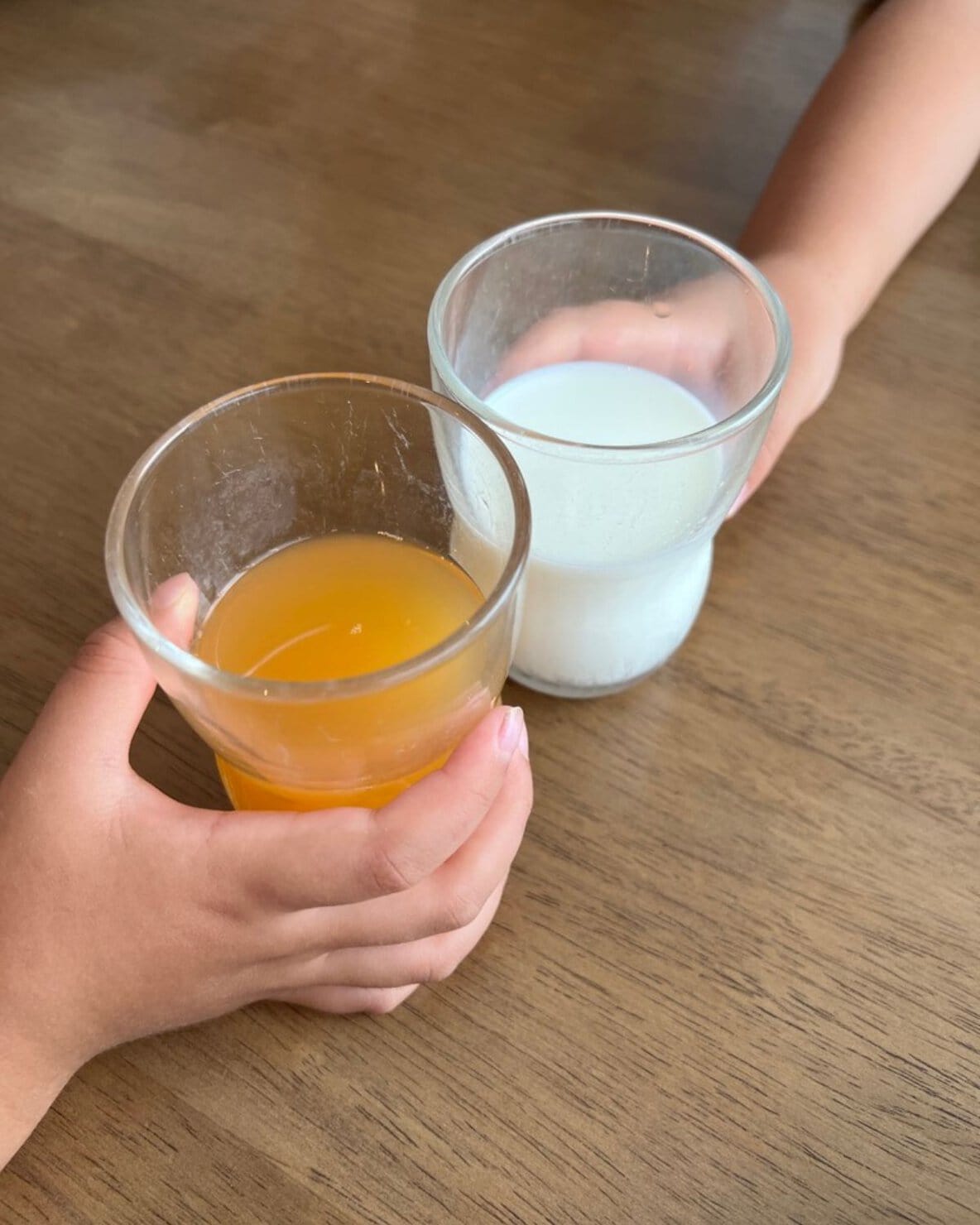 つよいこグラスに注いだ牛乳と野菜ジュースで乾杯する子ども