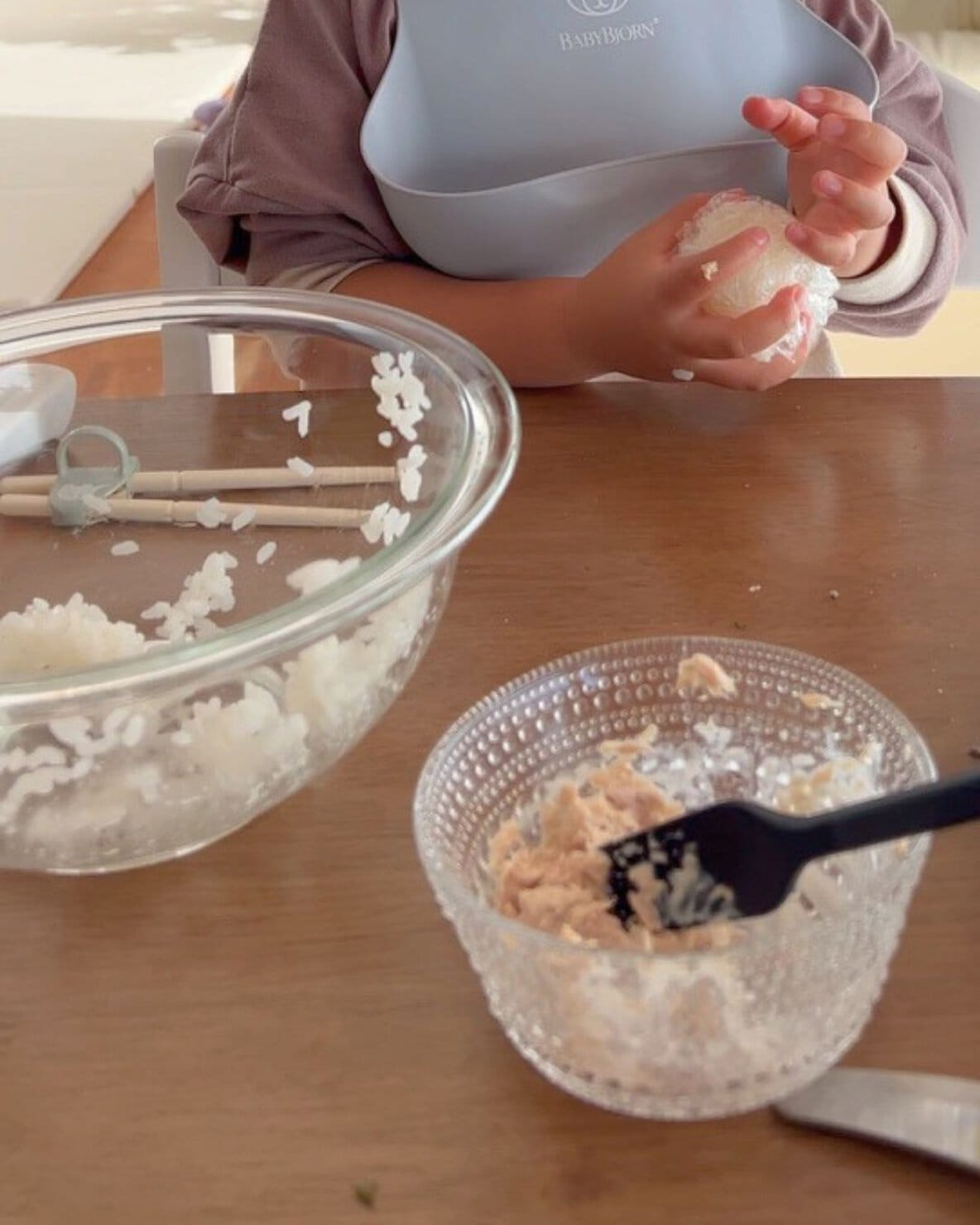 おにぎり用のご飯とイッタラカステヘルミに入ったツナマヨネーズでおにぎりを作る子ども