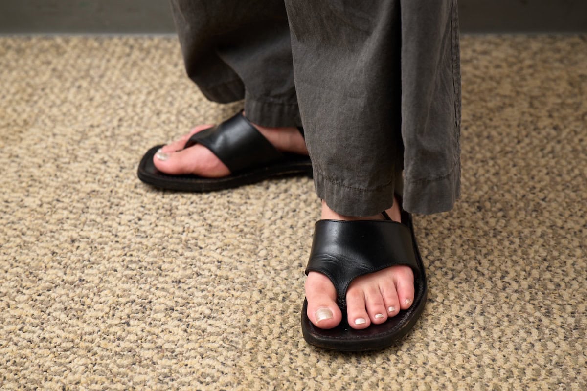 黒のレザートングサンダルにFINGER SUITのホワイトシルバーのペディキュアを合わせた足もと