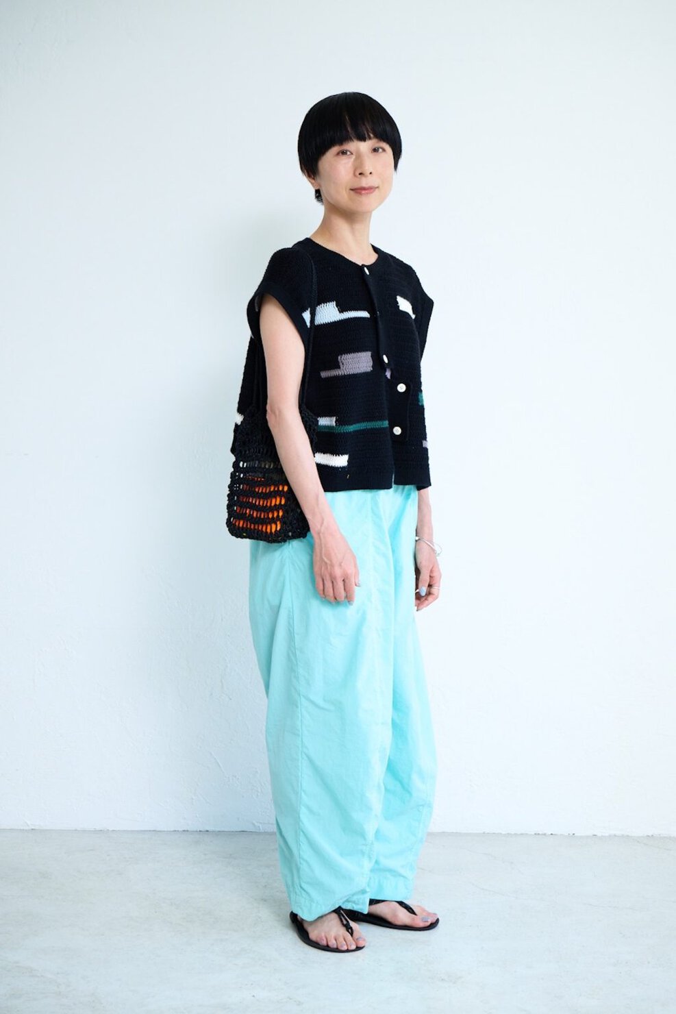 スニュウ デザイナー 雪浦聖子さんの私服ファッションスナップ。鮮やかなミントグリーンのパンツ×黒のニットベストで夏の装いにメリハリを