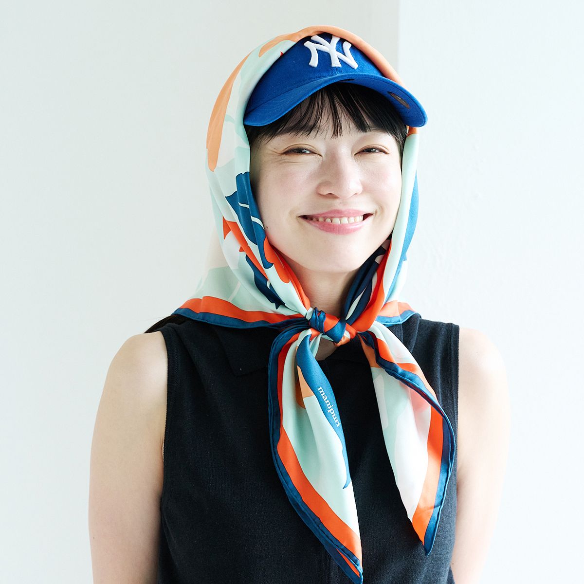 キャップと花柄の大判スカーフを合わせて、色で統一感がありつつも、華やかな装いに