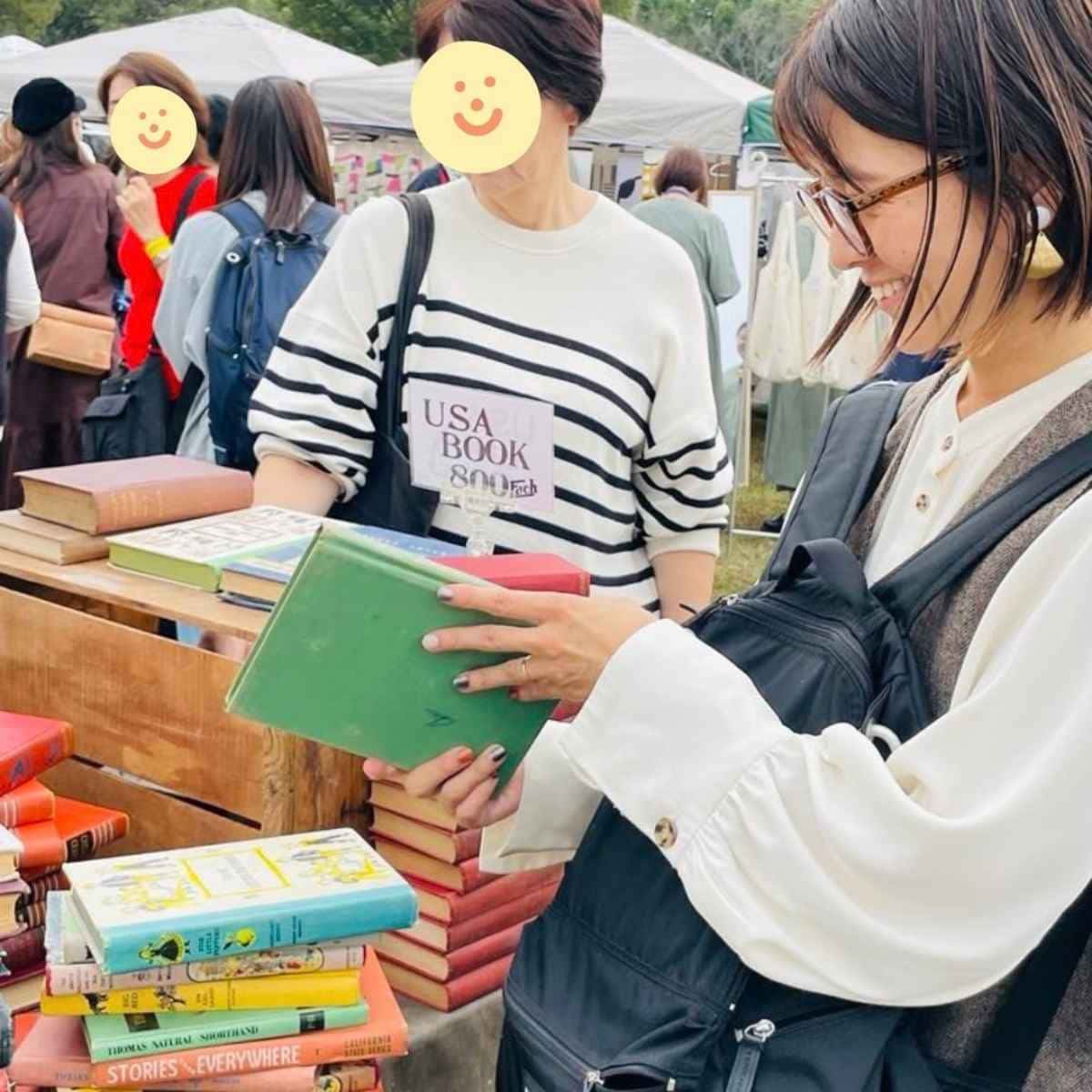 古い洋書を手に取って色合いや質感、表紙のデザインを見比べながら選ぶ様子