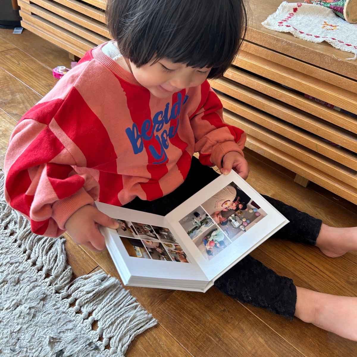 フォトブックを開いて自分の写真をみつけて喜ぶ娘